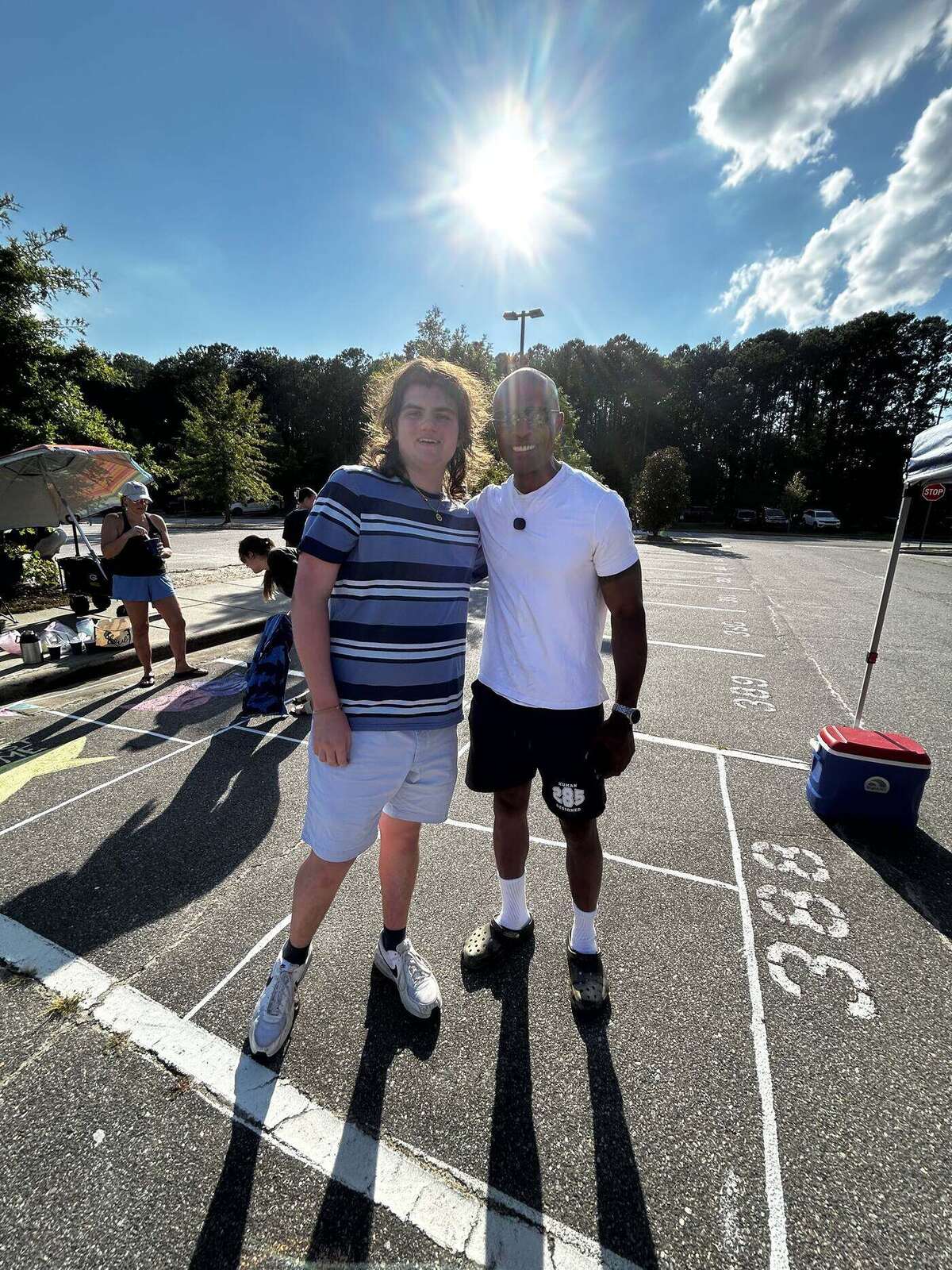 Apex Mayor Jacques Gilbert with a Class of 2027 senior, standing in a chalked parking space on a bright Sunday evening