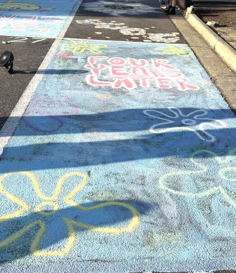 A chalked space reading Four Years Later, surrounded by large chalk flowers
