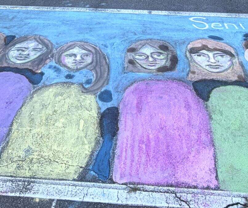 A chalked space with a hand-drawn portrait of seniors in graduation gowns and caps under the word Seniors
