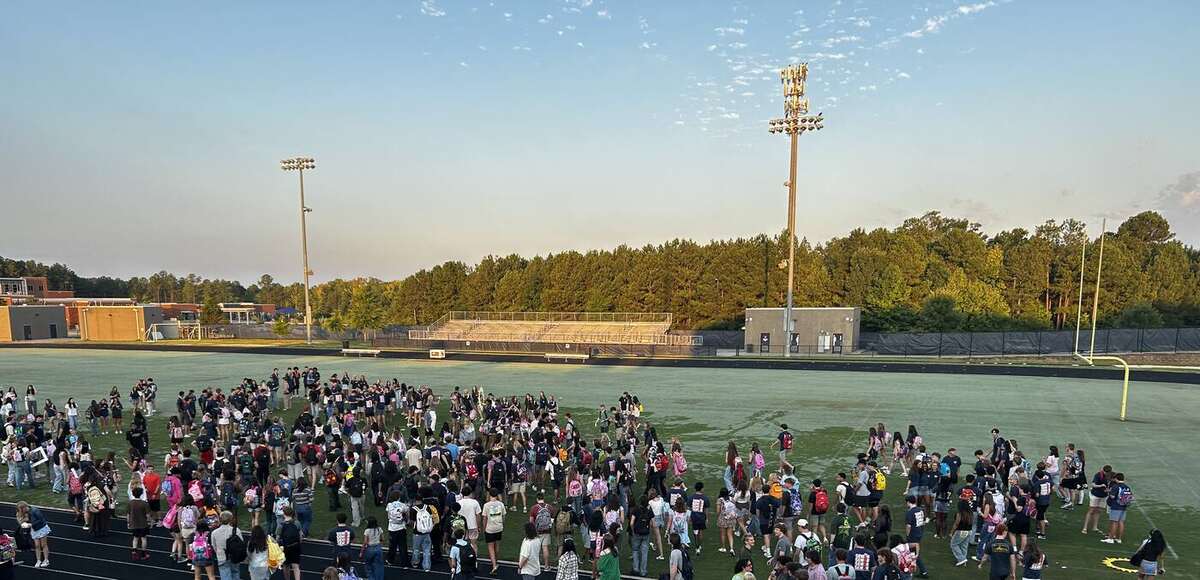 The Class of 2027 gathered across the AFHS field and track at sunrise, with the treeline and stadium lights behind them