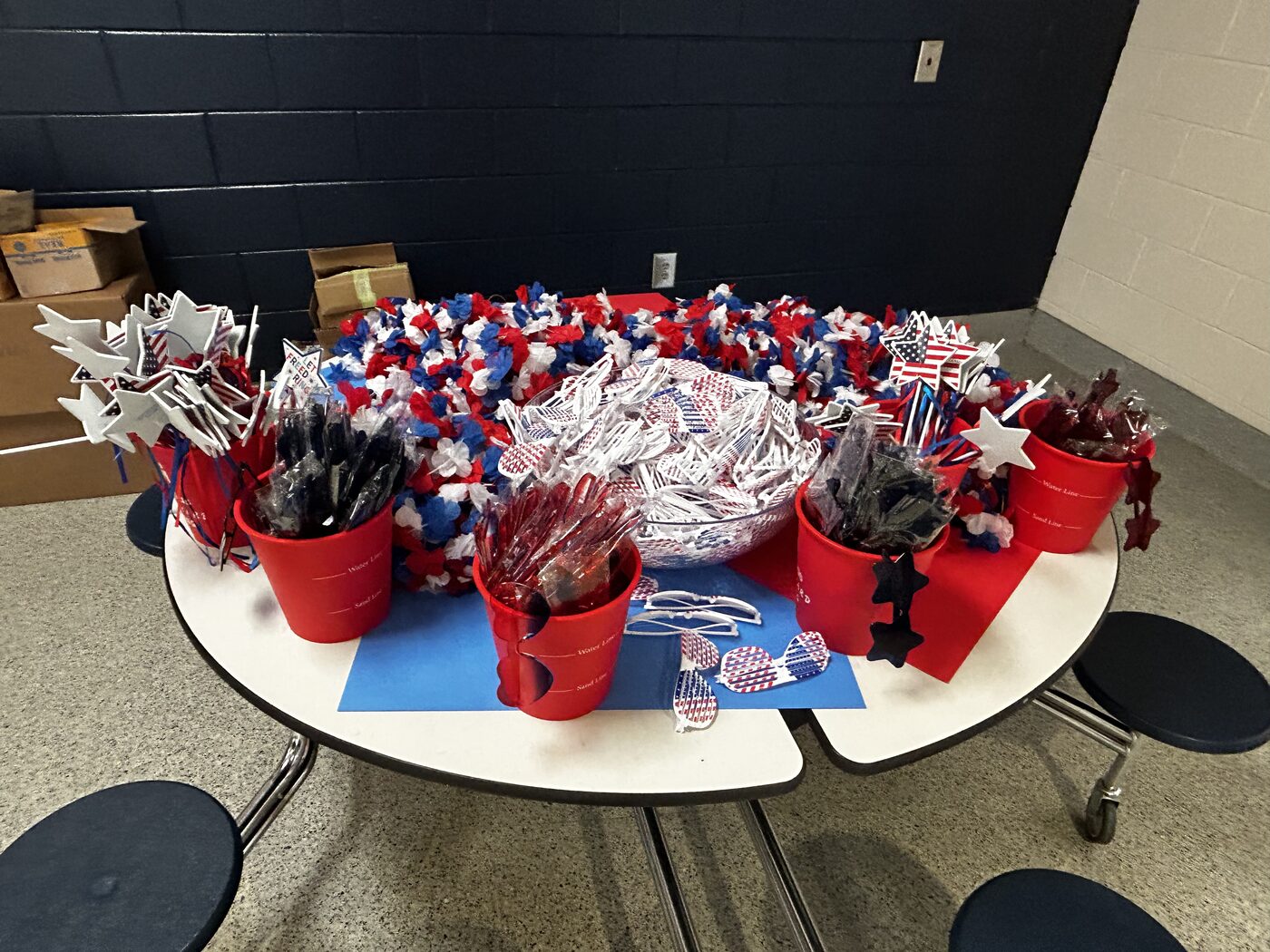 A table of red, white and blue leis, star wands, patriotic sunglasses and spirit favors